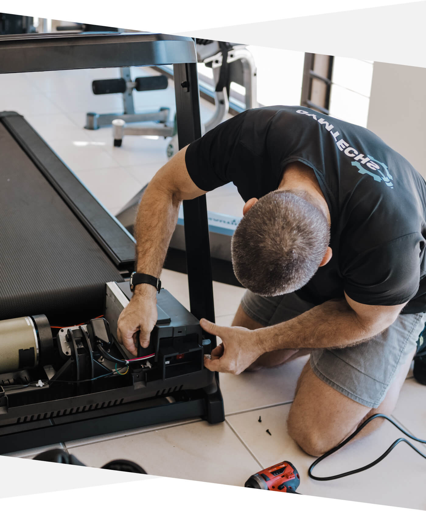 Gymtechs technician repairing a treadmill in a home gym